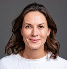 a headshot of a woman with wavy brown hair smiling at the camera